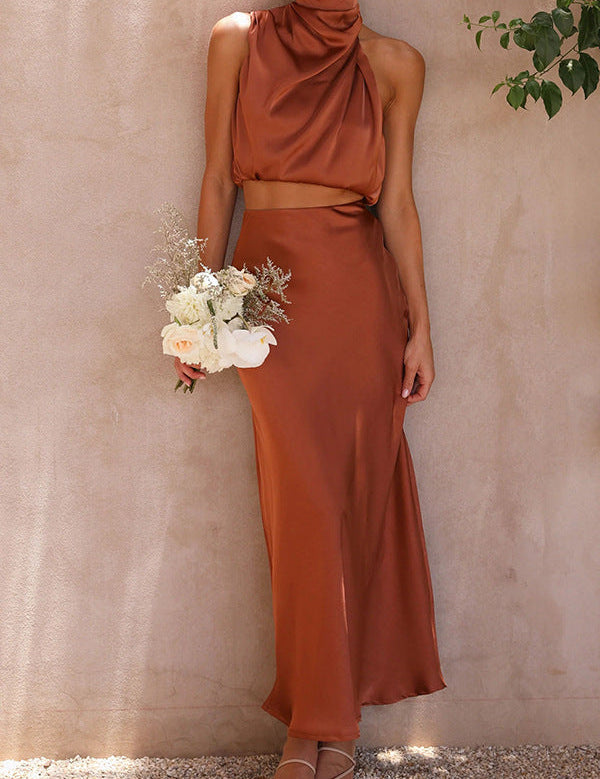 Abito lungo elegante color terracotta, senza maniche, con scollo all'americana, indossato da donna che tiene un bouquet di fiori bianchi e rosa.