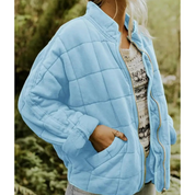 Giacca trapuntata azzurra da donna, con zip frontale e tasche laterali, indossata su maglia casual. Moda autunnale, abbigliamento outdoor.