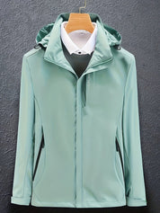 Giacca impermeabile verde menta con cappuccio, appesa su gruccia, su sfondo grigio. Design elegante, ideale per moda uomo e abbigliamento outdoor.