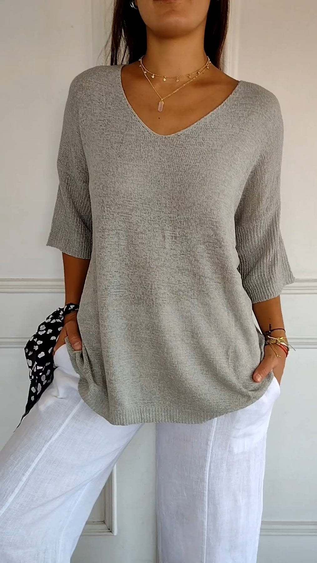 Maglione grigio donna a maniche corte, scollo a V, abbinato a pantaloni bianchi. Look casual ed elegante, moda femminile primavera estate.