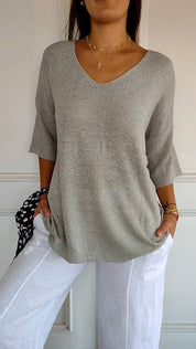 Maglione grigio donna a maniche corte, scollo a V, abbinato a pantaloni bianchi. Look casual ed elegante, moda femminile primavera estate.