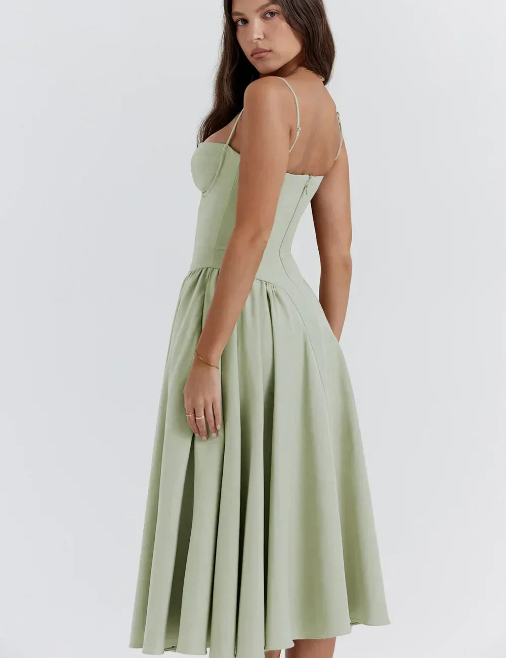 Abito midi verde salvia elegante, donna di profilo, spalline sottili, gonna svasata, moda femminile, abbigliamento estivo, stile sofisticato.