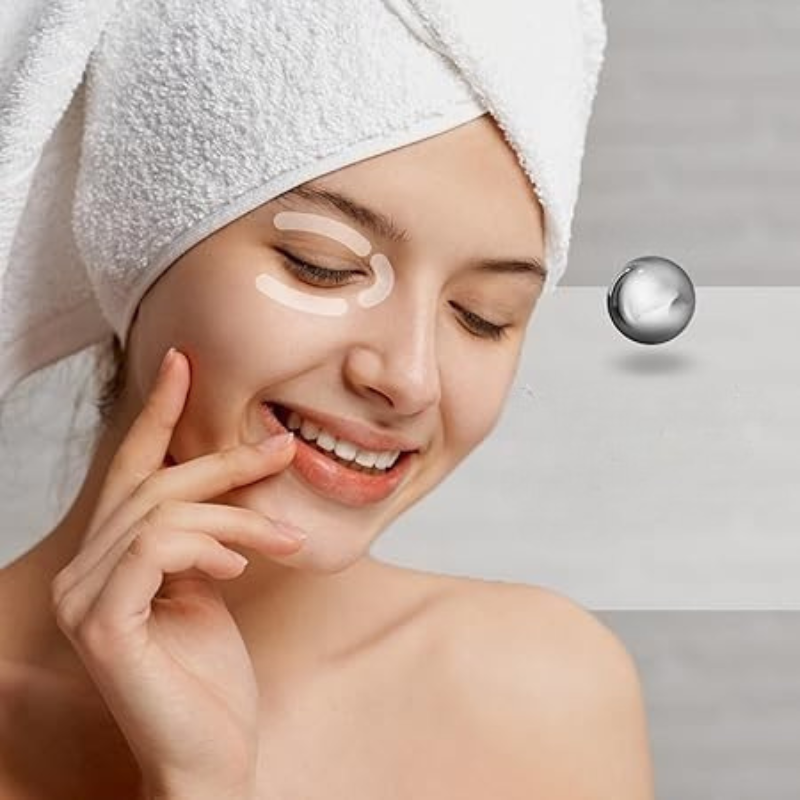 Donna sorridente con asciugamano bianco in testa applica crema contorno occhi. Cura della pelle, bellezza, trattamento viso, idratazione.