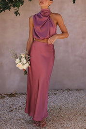 Abito da cerimonia elegante in raso rosa, top senza maniche con collo alto e gonna lunga. Donna con bouquet di fiori bianchi.