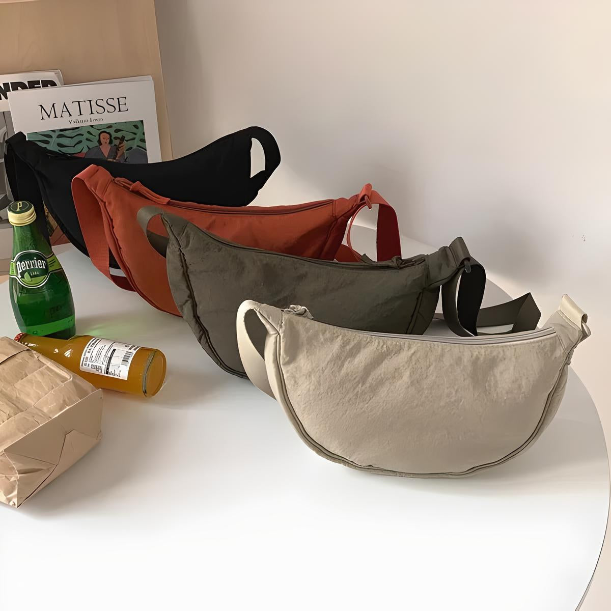 Quattro marsupi colorati su tavolo bianco, beige, verde, arancione, nero. Design moderno, casual. Riviste e bevande sullo sfondo. Accessori moda.