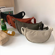Quattro marsupi colorati su tavolo bianco, beige, verde, arancione, nero. Design moderno, casual. Riviste e bevande sullo sfondo. Accessori moda.