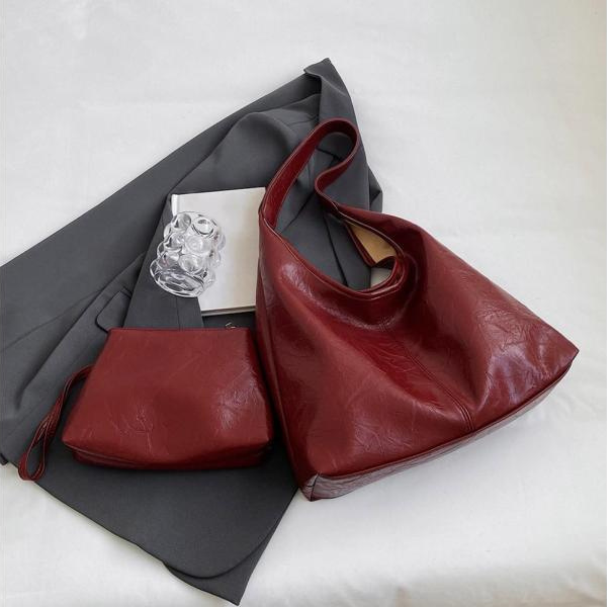 Borsa a spalla in pelle rossa con pochette abbinata su sfondo grigio. Design elegante, accessorio moda donna, ideale per shopping e uscite casual.