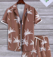 Completo estivo uomo marrone con palme bianche, camicia a maniche corte e pantaloncini coordinati. Moda casual, abbigliamento vacanze.