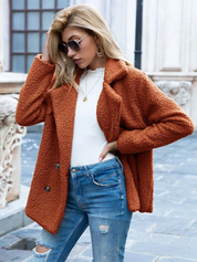 Giacca in pelliccia sintetica arancione, donna, abbinata a jeans strappati e maglia bianca. Moda autunnale, stile casual chic, occhiali da sole.