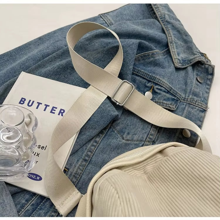 Giacca di jeans blu con cintura beige, borsa a coste e libro "Butter" su sfondo bianco. Accessori moda casual, stile urbano.