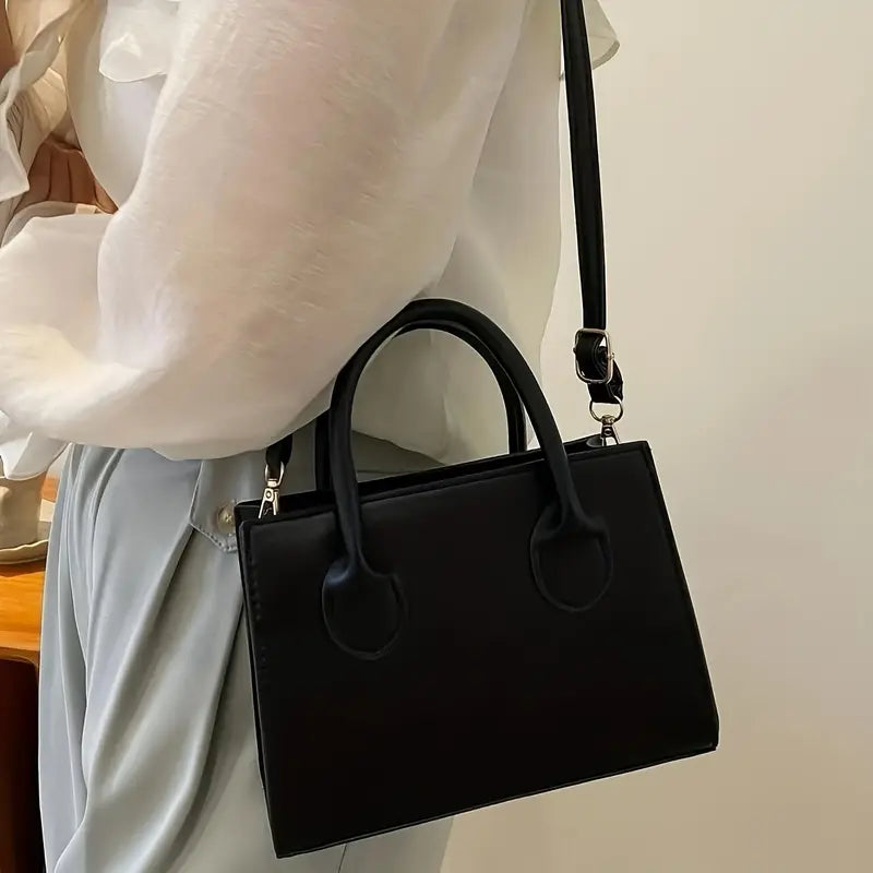Borsa a tracolla nera elegante in pelle, indossata su camicia bianca. Design minimalista, ideale per moda donna e accessori di lusso.