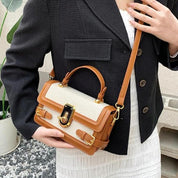 Donna con borsa a tracolla in pelle marrone e tessuto beige, giacca nera e abito bianco. Accessorio moda elegante, stile casual chic.