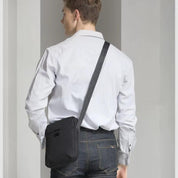 Uomo con camicia bianca e jeans indossa borsa a tracolla nera. Accessorio moda casual, ideale per lavoro e tempo libero.