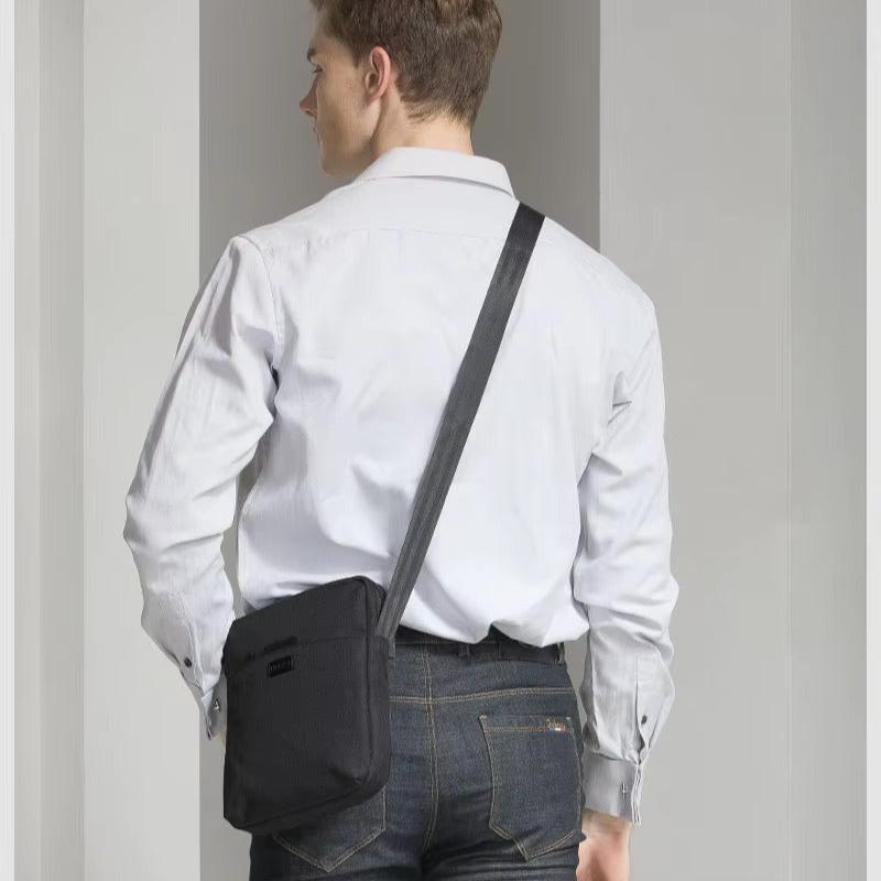 Uomo con camicia bianca e jeans indossa borsa a tracolla nera. Accessorio moda casual, ideale per lavoro e tempo libero.