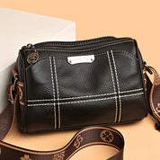 Borsa a tracolla in pelle nera con cuciture bianche, cerniera superiore e tracolla regolabile marrone. Design elegante e moderno per donna.