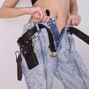 Jeans a vita alta in denim chiaro con cintura nera e tasche multiple, indossati da una persona. Design moderno e funzionale per moda urbana.