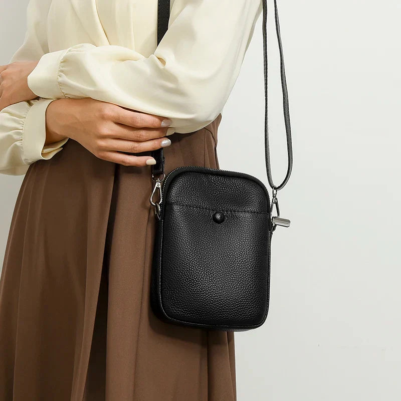 Borsa a tracolla nera in pelle, design elegante e compatto, indossata da una donna. Accessorio moda versatile per ogni occasione.