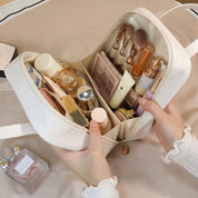 Borsa cosmetica bianca aperta con trucchi e accessori, tra cui rossetti, pennelli e profumo. Organizzatore da viaggio elegante e funzionale.