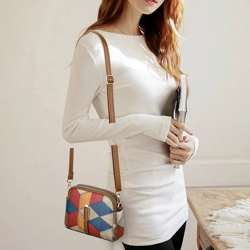 Donna con borsa a tracolla multicolore in pelle, design geometrico, indossa maglia bianca. Accessorio moda femminile elegante e moderno.