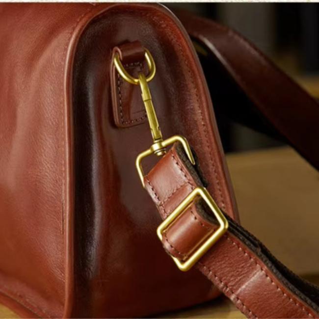 Borsa in pelle marrone con fibbia dorata e tracolla regolabile. Design elegante e raffinato, ideale per moda e accessori di lusso.