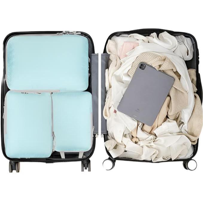 Valigia aperta con organizer azzurri e vestiti, tablet grigio su tessuti chiari. Bagaglio da viaggio organizzato, accessori valigia.