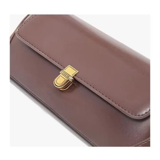 Elegante borsa a tracolla in pelle marrone con chiusura dorata, design minimalista, accessorio moda donna, ideale per ogni occasione.
