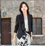 Donna con abito floreale bianco e nero e blazer nero, cammina all'aperto. Moda femminile elegante, abbigliamento casual chic, stile urbano.