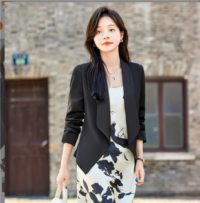 Donna con abito floreale bianco e nero e blazer nero, cammina all'aperto. Moda femminile elegante, abbigliamento casual chic, stile urbano.