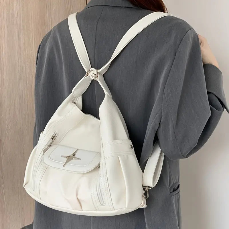 Zaino bianco in pelle su donna con giacca grigia, design moderno, tasca frontale con zip, ideale per moda urbana e viaggi.