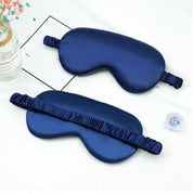 Maschera per dormire in seta blu scuro su sfondo bianco, con elastico arricciato. Accessorio per il sonno, relax e benessere.