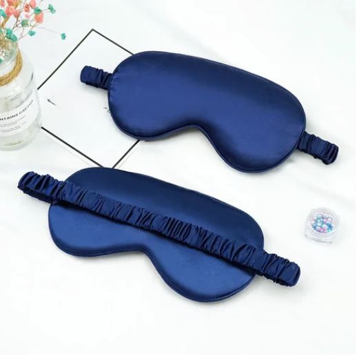 Maschera per dormire in seta blu scuro su sfondo bianco, con elastico arricciato. Accessorio per il sonno, relax e benessere.