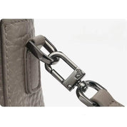 Gancio in metallo lucido su borsa in pelle grigia, dettaglio di alta qualità, accessorio moda elegante, design moderno e resistente.