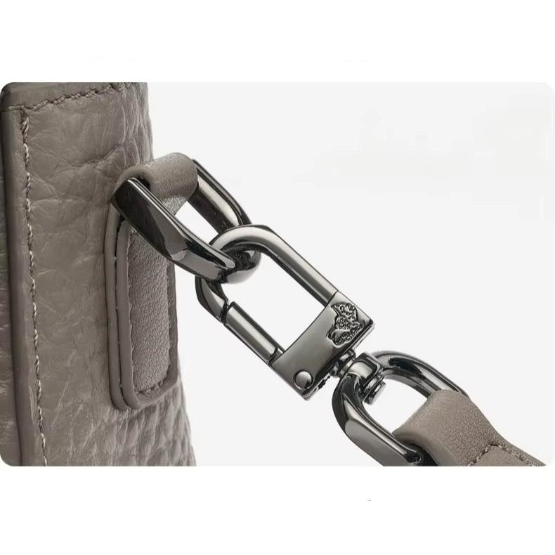 Gancio in metallo lucido su borsa in pelle grigia, dettaglio di alta qualità, accessorio moda elegante, design moderno e resistente.
