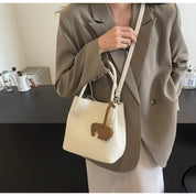 Donna con borsa a tracolla bianca in pelle, design elegante, abbinata a blazer beige. Accessorio moda femminile, stile casual chic.
