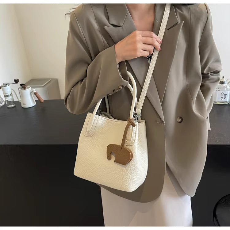Donna con borsa a tracolla bianca in pelle, design elegante, abbinata a blazer beige. Accessorio moda femminile, stile casual chic.