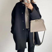 Cappotto nero elegante donna, abbinato a borsa a tracolla beige, moda autunno inverno, stile casual chic, outfit femminile moderno.
