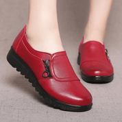 Scarpe da donna rosse in pelle con cerniera laterale, suola nera antiscivolo. Calzature comode e alla moda per uso quotidiano.