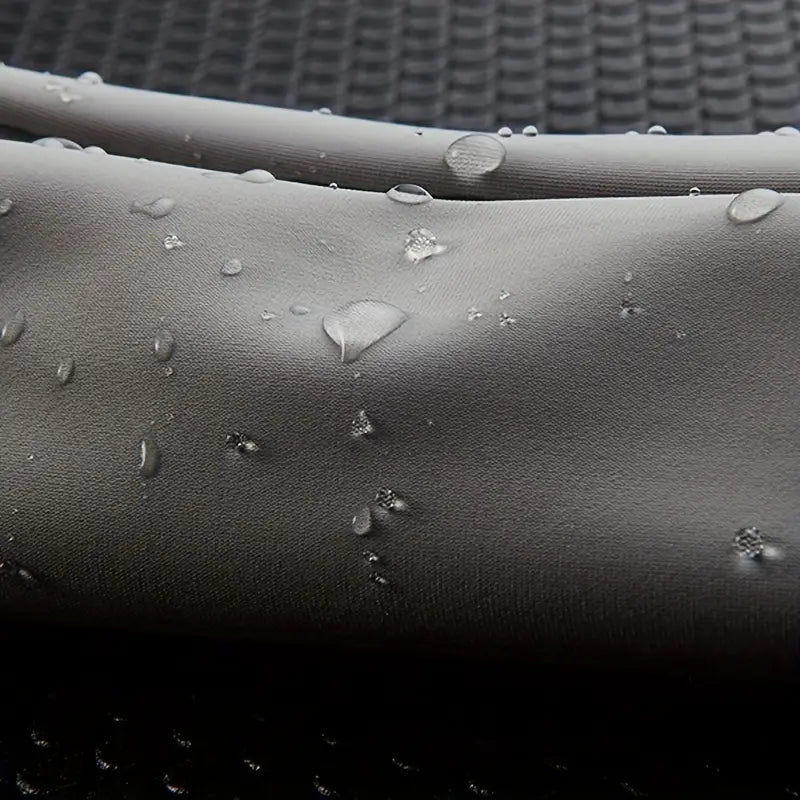 Tessuto impermeabile grigio con gocce d'acqua, texture liscia, ideale per abbigliamento outdoor e sportivo. Resistente e idrorepellente.