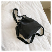 Borsa a tracolla nera su letto bianco, design minimalista, tessuto resistente, ideale per moda casual e quotidiana. Accessorio versatile ed elegante.