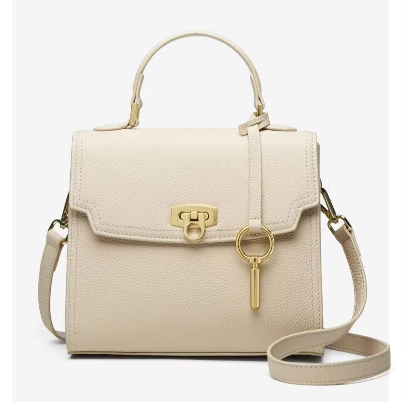 Borsa a mano in pelle beige con tracolla regolabile, chiusura a scatto dorata e portachiavi. Elegante accessorio moda donna.