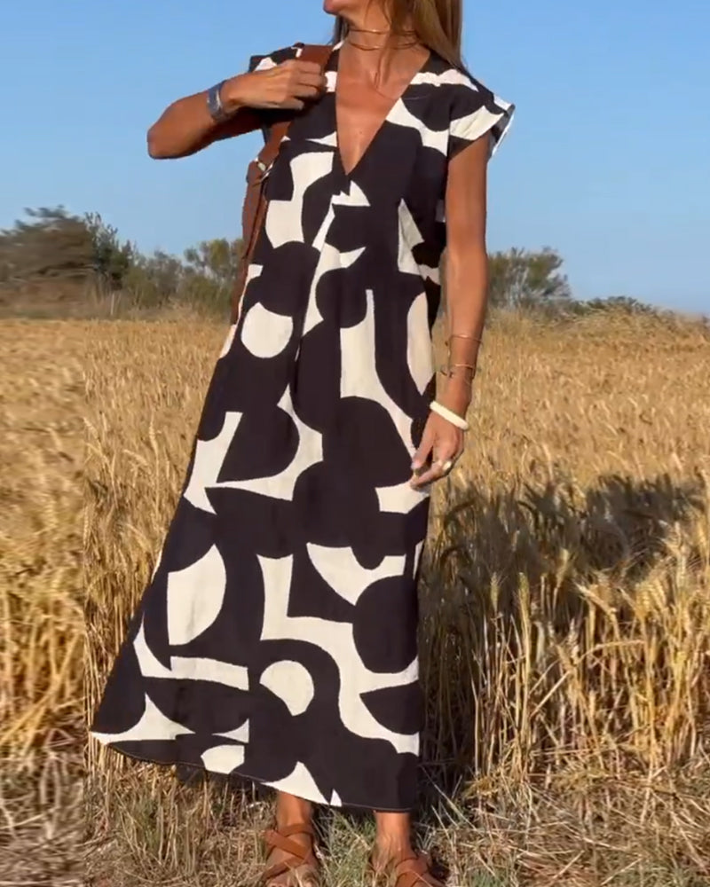 Abito lungo estivo con stampa astratta bianco e nero, indossato in un campo di grano. Moda donna, abbigliamento casual elegante.