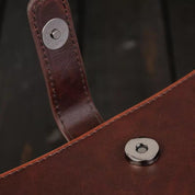 Borsa in pelle marrone con chiusura magnetica in metallo, dettaglio elegante e resistente, accessorio moda di alta qualità.