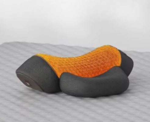 Cuscino ergonomico arancione e nero su superficie grigia, design a nido d'ape, supporto cervicale, ideale per comfort e postura corretta.