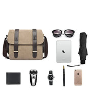 Borsa a tracolla in tela beige con fibbie marroni, occhiali da sole, ombrello nero, iPad, iPhone, portafoglio, rasoio, orologio e penna stilografica.
