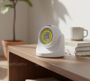 Lampada LED bianca su tavolo in legno, luce gialla accesa, pianta in vaso e tazza sullo sfondo. Design moderno, illuminazione interna efficiente.