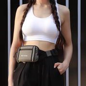Donna con top sportivo bianco e marsupio nero, capelli intrecciati, posa casual. Accessori moda, abbigliamento sportivo, stile urbano.
