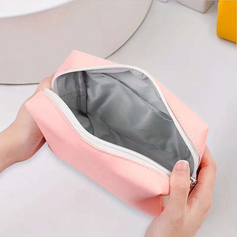 Astuccio da viaggio rosa in tessuto impermeabile con cerniera aperta, ideale per cosmetici e accessori. Design compatto e pratico.