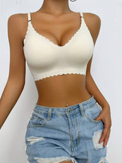 Modella indossa reggiseno bianco senza cuciture con bordo ondulato e shorts di jeans strappati. Intimo comodo, moda estiva, abbigliamento casual.