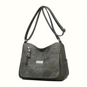 Borsa a tracolla in pelle sintetica grigia con tasche multiple e cerniere, design elegante e funzionale, ideale per uso quotidiano e lavoro.