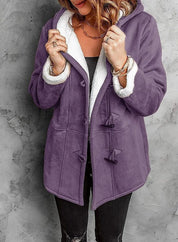 Giacca invernale viola con cappuccio, chiusura a alamari, interno in pelliccia sintetica bianca, indossata da donna. Moda autunno inverno.